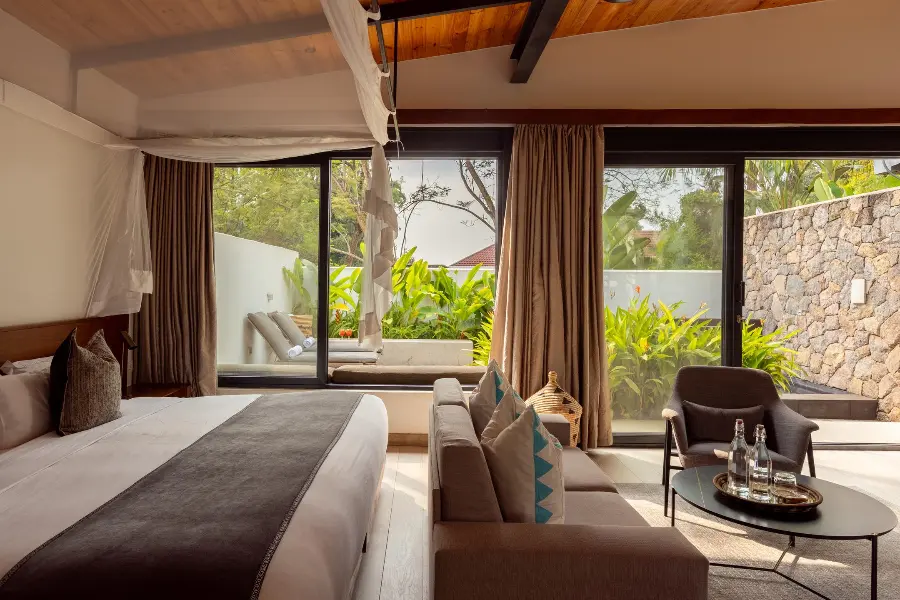 A contemporary yet comfortable suite at Hemingways Retreat in Kigali looking out over loungers and a garden | Go2Africa
