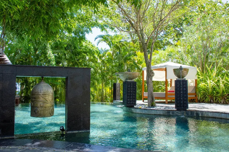 A pool sheltered by trees with a 4-poster day bed set alongside | Go2Africa
