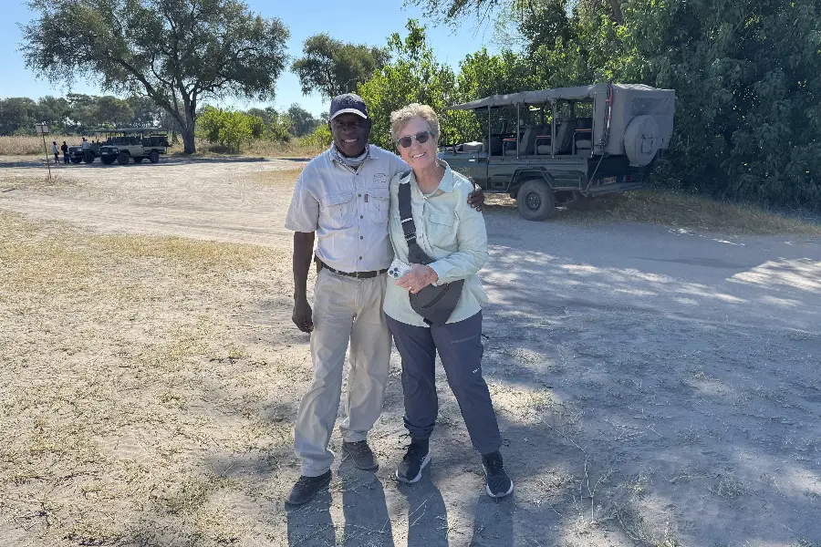 Uma mulher com o seu guia de safari em frente a um veículo de caça Feline Fields | Go2Africa