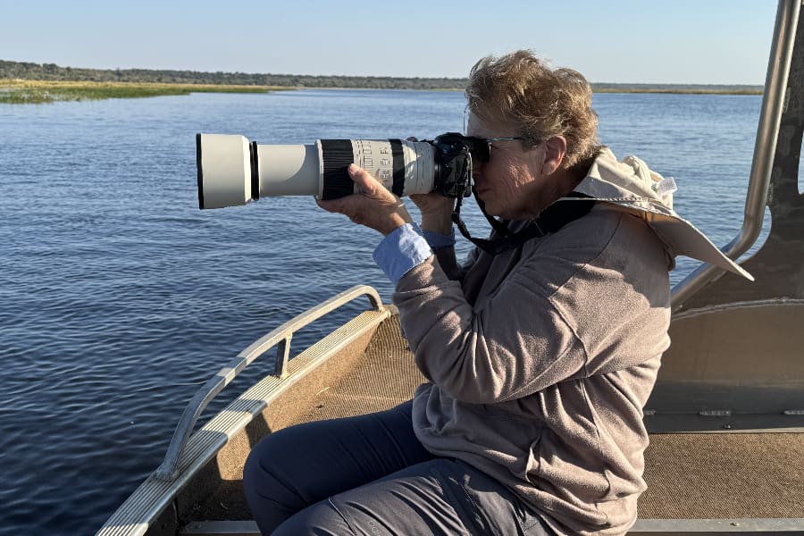 Uma mulher senta-se num barco no meio de um rio com a máquina fotográfica apontada à cara | Go2Africa