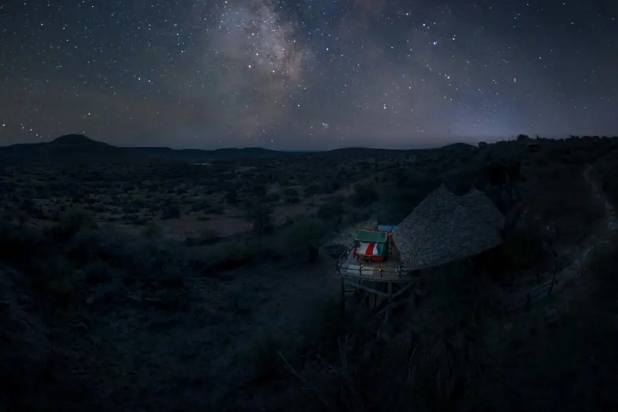 Ein Sternenbett auf einer erhöhten Plattform steht unter einem weitläufigen Sternenhimmel | Go2Africa