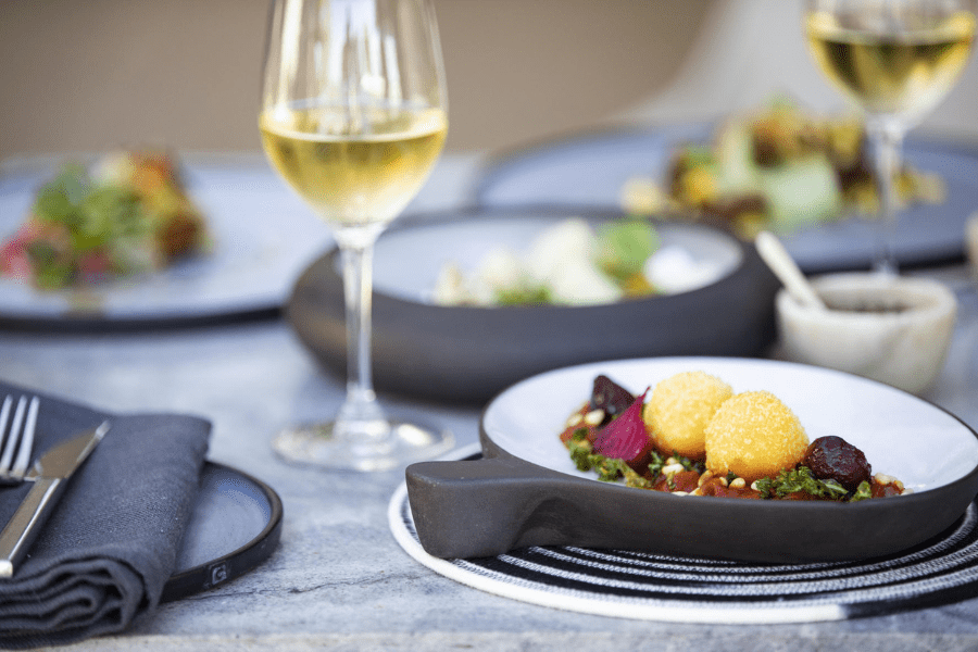 Grande plano de um prato vibrante e vinho no Singita Lebombo | Go2Africa