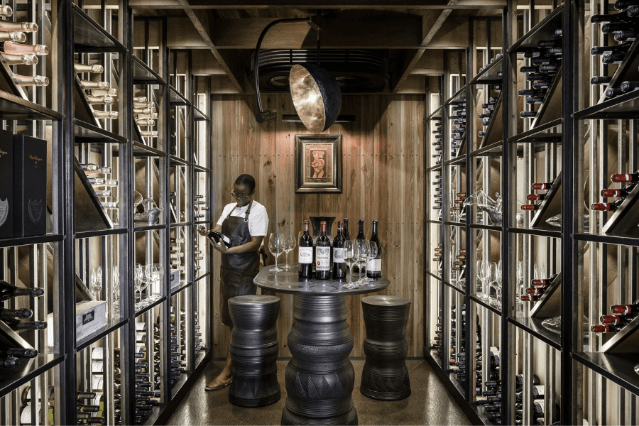 Sommelier seleciona uma garrafa de vinho na adega climatizada do Xigera Safari Lodge | Go2Africa