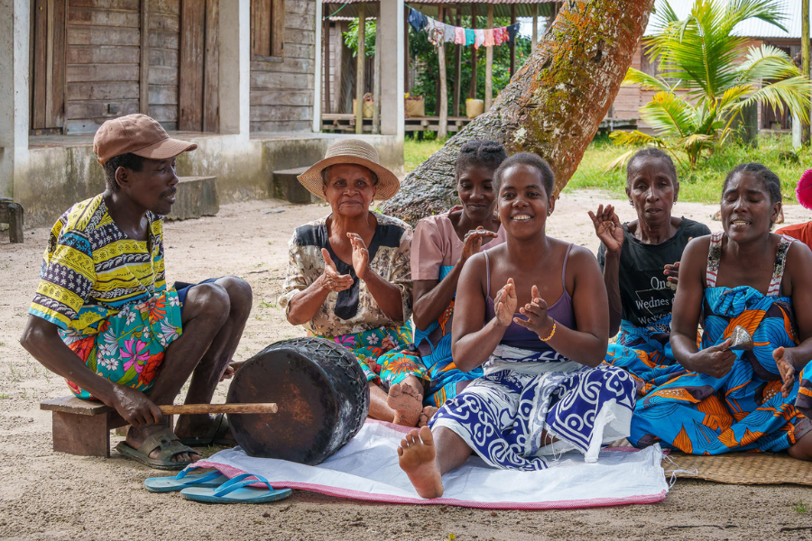 Group of Malagasy locals sitting outdoors, clapping and playing music together | Go2Africa