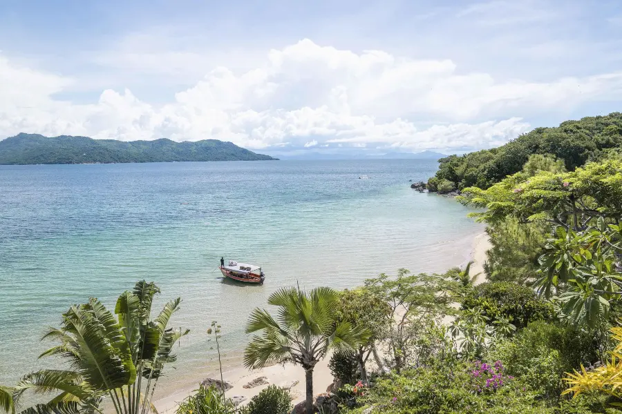 View over a calm bay with a small boat near a tropical shoreline | Go2Africa