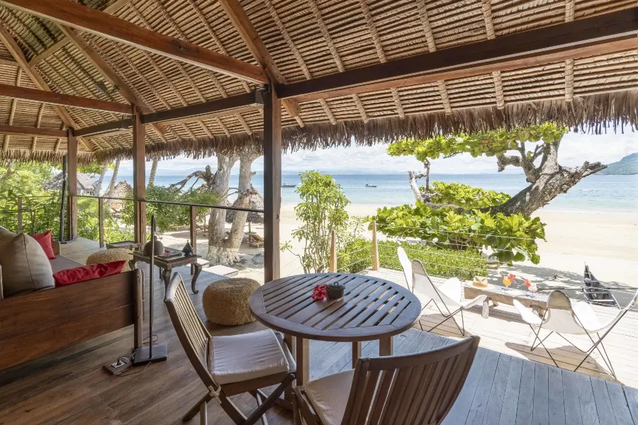Open-air beachfront room with wooden deck overlooking a sandy beach and ocean | Go2Africa