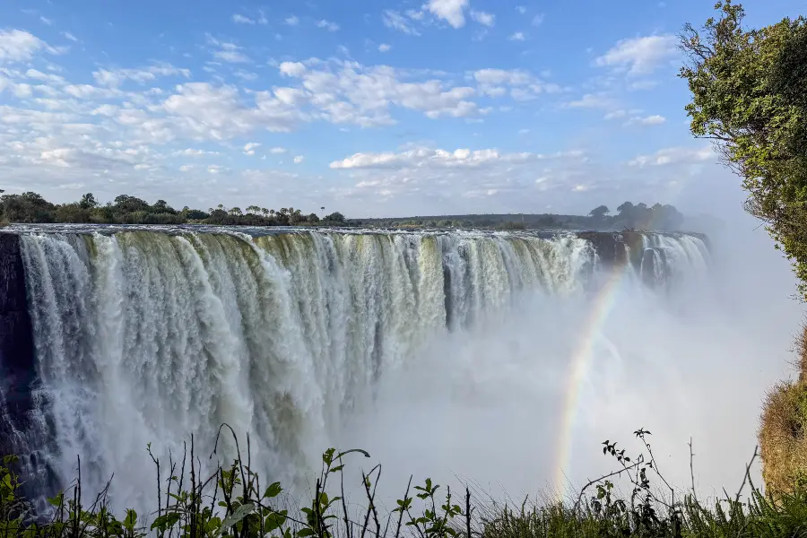 A rainbow across Victoria Falls main falls viewpoint | Go2Africa