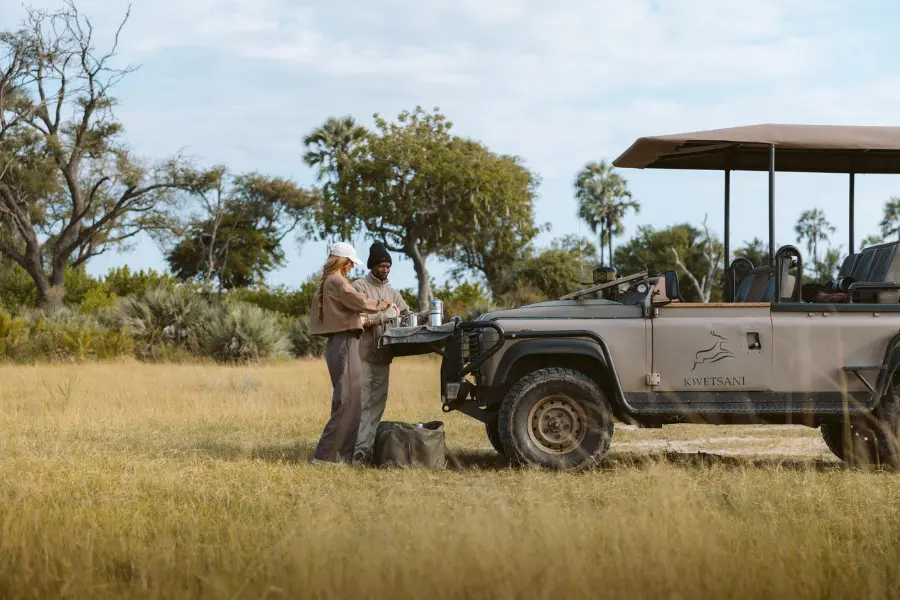 Guest and guide preparing refreshments beside a safari vehicle in Botswana | Go2Africa