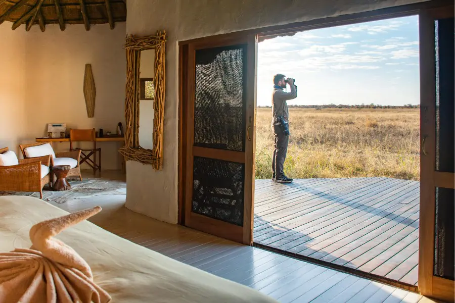 Solo traveller standing on a private deck overlooking the savannah from a safari lodge | Go2Africa